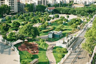 Luftbildaufnahme plaza mit Bäumen und Gebäuden. Zu sehen ist eine Grüne Oase / ein Park zwischen verschiendenen Wohngebäuden