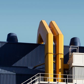 An industrial building photographed from the outside with 2 large yellow pipes running up it