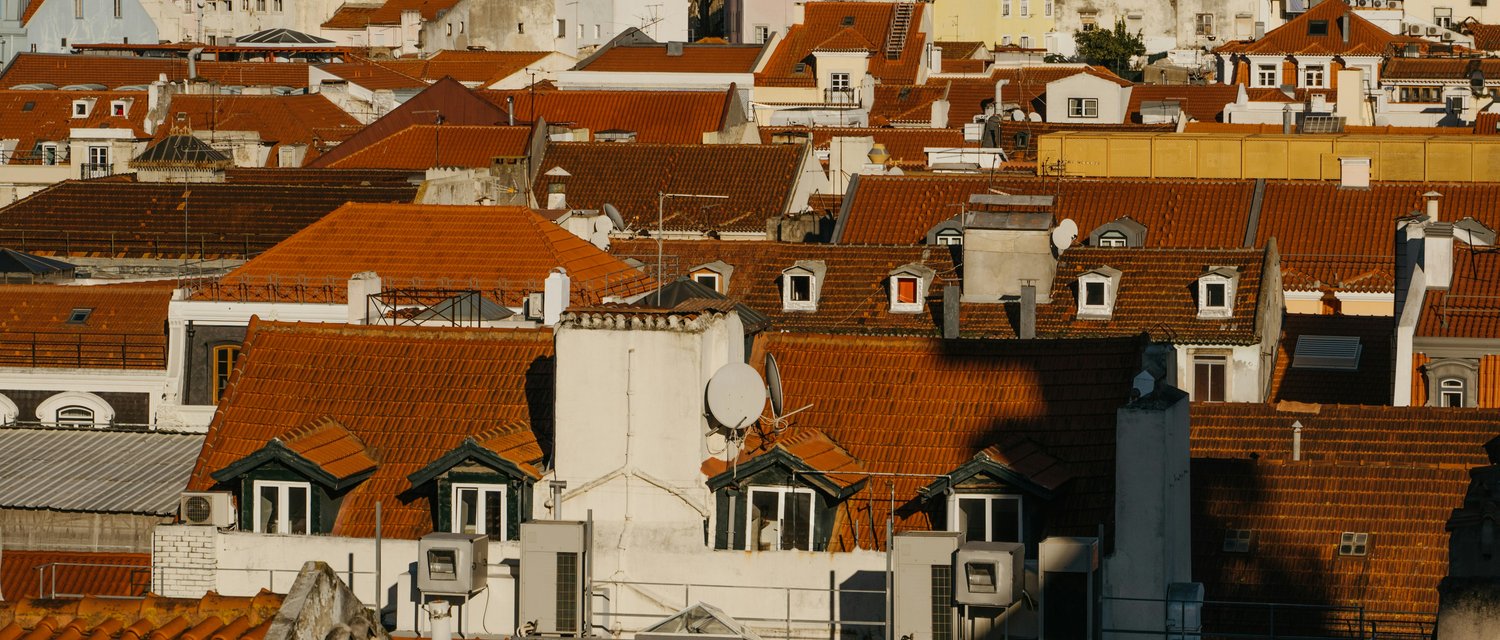 Ausblick von Oben, über einen Stadtteil von Lisabon. Es sind hauptsächlich Dächer von Mehrparteienhäuser zu sehen.